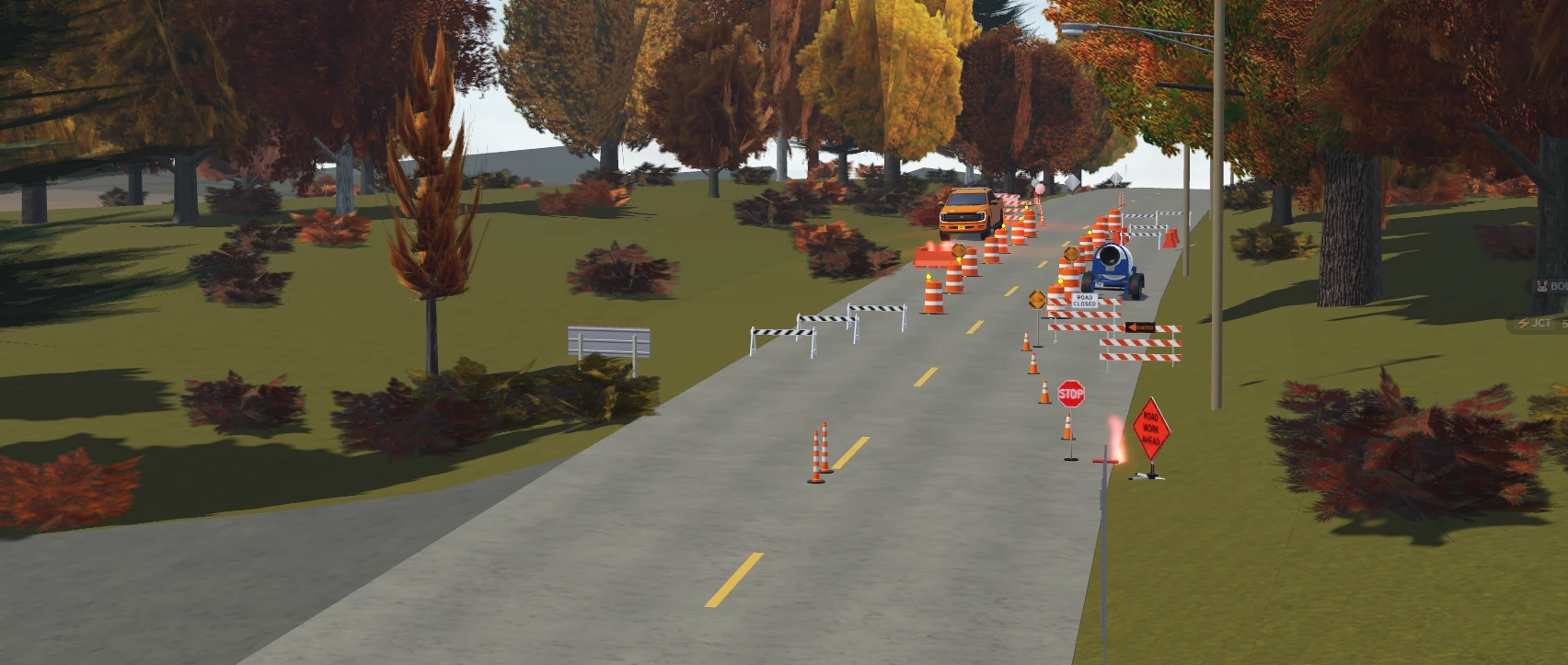 A lane closure with cones, barrels and a road closed sign on an autumn road.